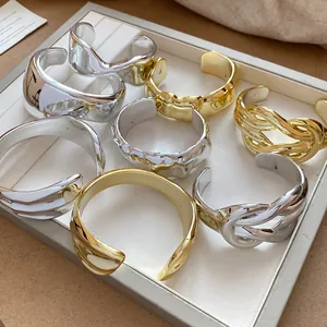 Close-up view of gold and silver chunky geometric open cuffs with a shiny crumpled texture