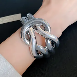Detail shot of a bold silver twisted knot acrylic cuff bracelet worn on a wrist