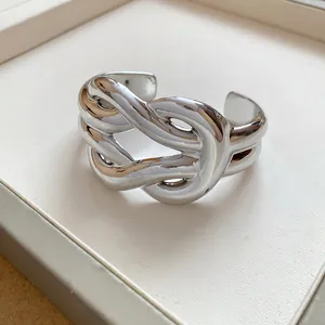 Detailed view of a chunky silver-colored cuff bracelet with a twisted knot design