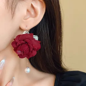 Elegant close-up detail of a vintage dark red fabric rose earring with a drop pearl
