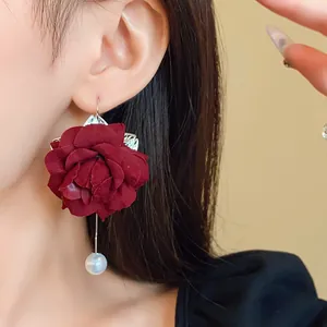 Detailed close-up of a dark red fabric rose earring with pearl drop on a model.