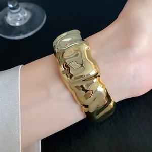Close-up of a chunky gold cuff bracelet with a stylish wrinkled geometric design on a wrist