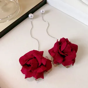 Close-up view of elegant long drop earrings featuring red fabric roses and pearls