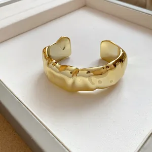 Close-up of golden wrinkled geometric open cuff bracelet with high-shine finish
