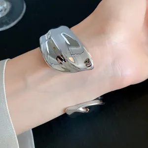 Macro view of a shiny silver geometric cuff bracelet with a wrinkled texture on wrist