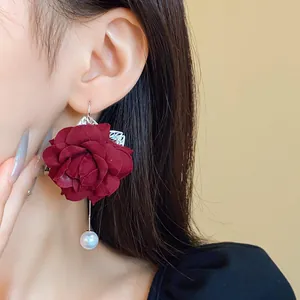 Close-up of elegant burgundy fabric flower earrings with white faux pearl drop detail.