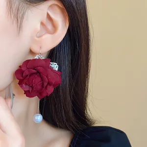 Close-up of retro dark red fabric flower earrings with hanging artificial pearl detail.