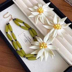 Elegant 3D white flower earrings with olive green beaded necklace in jewelry box.