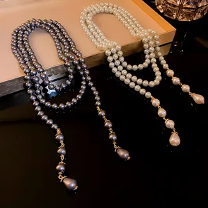 Elegant French style layered pearl necklaces in white and grey colors on a gold tray