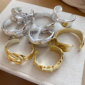 Close-up of glossy pleated geometric open bangles in gold and silver finishes