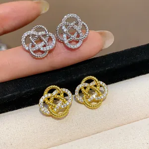 Vue détaillée d'élégantes boucles d'oreilles fleur en zircon avec finitions or et argent.