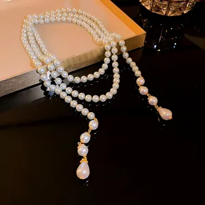 Elegant long multi-layer pearl necklace with vintage gold accents and teardrop pendants.