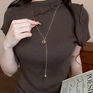 Vintage resin pendant necklace with adjustable gold chain over brown knit sweater