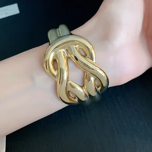 Chunky gold-tone acrylic knotted cuff bracelet on model's wrist