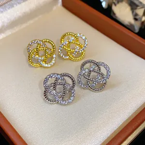 Détail de boucles d'oreilles fleurs ajourées en or et argent avec pavé de zircons brillants