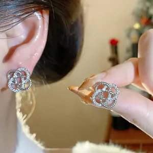 Détail de boucles d'oreilles fleurs ajourées avec zircons étincelants portées