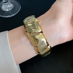 Close-up of a glossy gold pleated acrylic cuff bracelet highlighting its texture