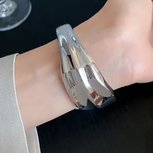 Detailed view of a shiny silver wrinkled geometric acrylic open bangle on a wrist