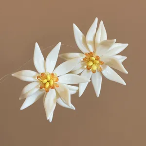 Detailed macro view of white petal floral earrings with vibrant yellow center beads