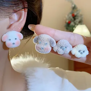 Close-up of cute flocked dog stud earrings in various colors on hand and ear