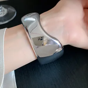Close-up view of a chunky silver irregular geometric acrylic bangle worn on a female wrist