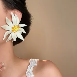 Close-up of a large 3D white flower earring worn by a model for a beach holiday look.