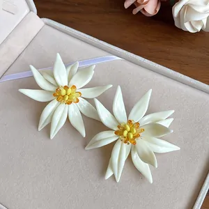 Close-up view of elegant white 3D flower earrings featuring vibrant yellow beaded centers