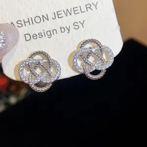 Gros plan de boucles d'oreilles fleurs évidées serties de zircons aux détails argentés