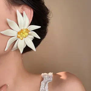 Macro detail view of an oversized white floral earring with amber beads on an Asian model