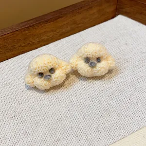 Detailed close-up of cute cream colored poodle dog stud earrings with textured finish
