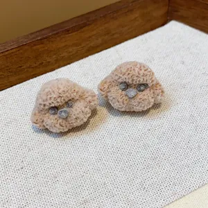 Macro view of cute fluffy poodle dog stud earrings with soft beige fur texture detail