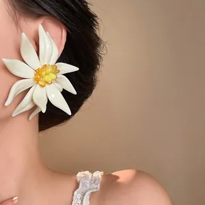 Close-up of a large white flower earring with yellow center worn on model's ear