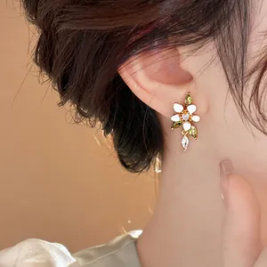 Nahaufnahme des mit 14K Gold überzogenen Blumenohrrings mit Zirkon und Emaille