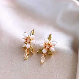 Detailansicht eleganter Blumenohrringe mit weißer Emaille und funkelnden Zirkonia-Steinen
