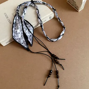 Close-up of bohemian paisley silk scarf waist chain with decorative wooden beads.