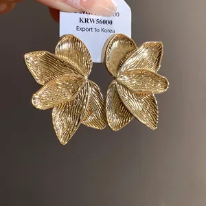 Makro-Detail von goldenen Blütenblatt-Ohrringen mit strukturierter Oberfläche und Glanz