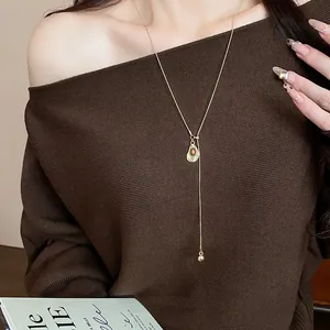 Detailed shot of retro Maillard style resin pendant necklace on brown sweater.