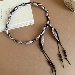 Detail view of a bohemian woven waist chain featuring silk scarf wrap and wooden beads