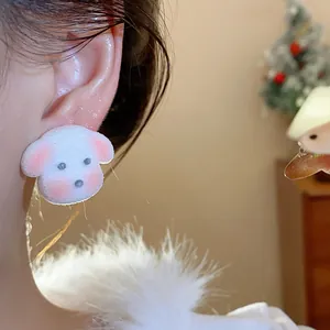Close-up of a cute white flocked puppy stud earring worn on an ear with a soft winter vibe.