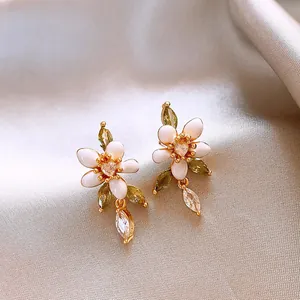 Detailansicht eleganter Blumenohrringe mit weißen Emaille-Blüten und olivgrünen Zirkonia.