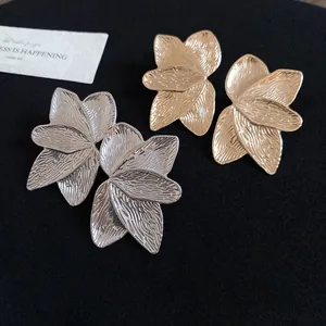 Detailansicht von Metallohrringen mit Blütenblattstruktur in Gold- und Silberoptik