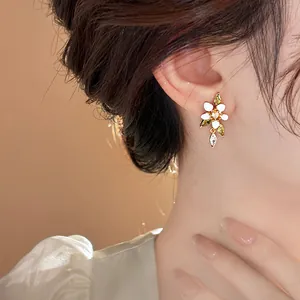 Detailansicht von 14K vergoldeten Blumenohrringen mit weißen Blüten und Zirkonsteinen