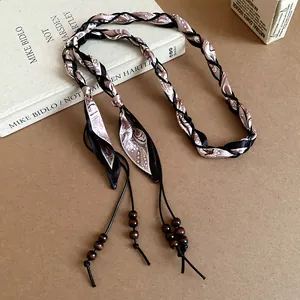 Close-up of bohemian silk scarf braided waist chain with vintage pattern and wooden beads