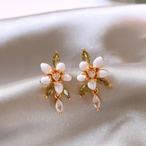 Detailansicht von weißen Emaille-Blumenohrringen mit grünen Zirkonia und Herzmitte