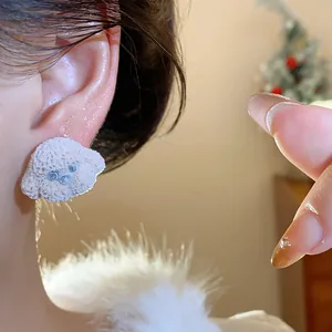 Close-up shot of a cute fuzzy poodle stud earring with silver needles worn on an ear