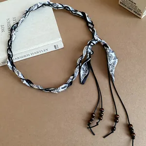 Detail of a bohemian silk scarf belt with braided cord and wooden beads.