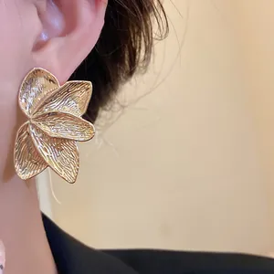 Detailansicht großer goldener Blütenohrringe mit Vintage-Struktur am Ohr getragen