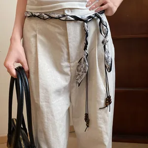 Detail of bohemian silk scarf braided waist chain with wooden beads on linen trousers