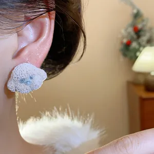 Close-up detail of a cute poodle-shaped plush stud earring being worn on an earlobe