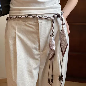 Close-up detail of a Bohemian style braided silk scarf belt with wooden beads and tassels